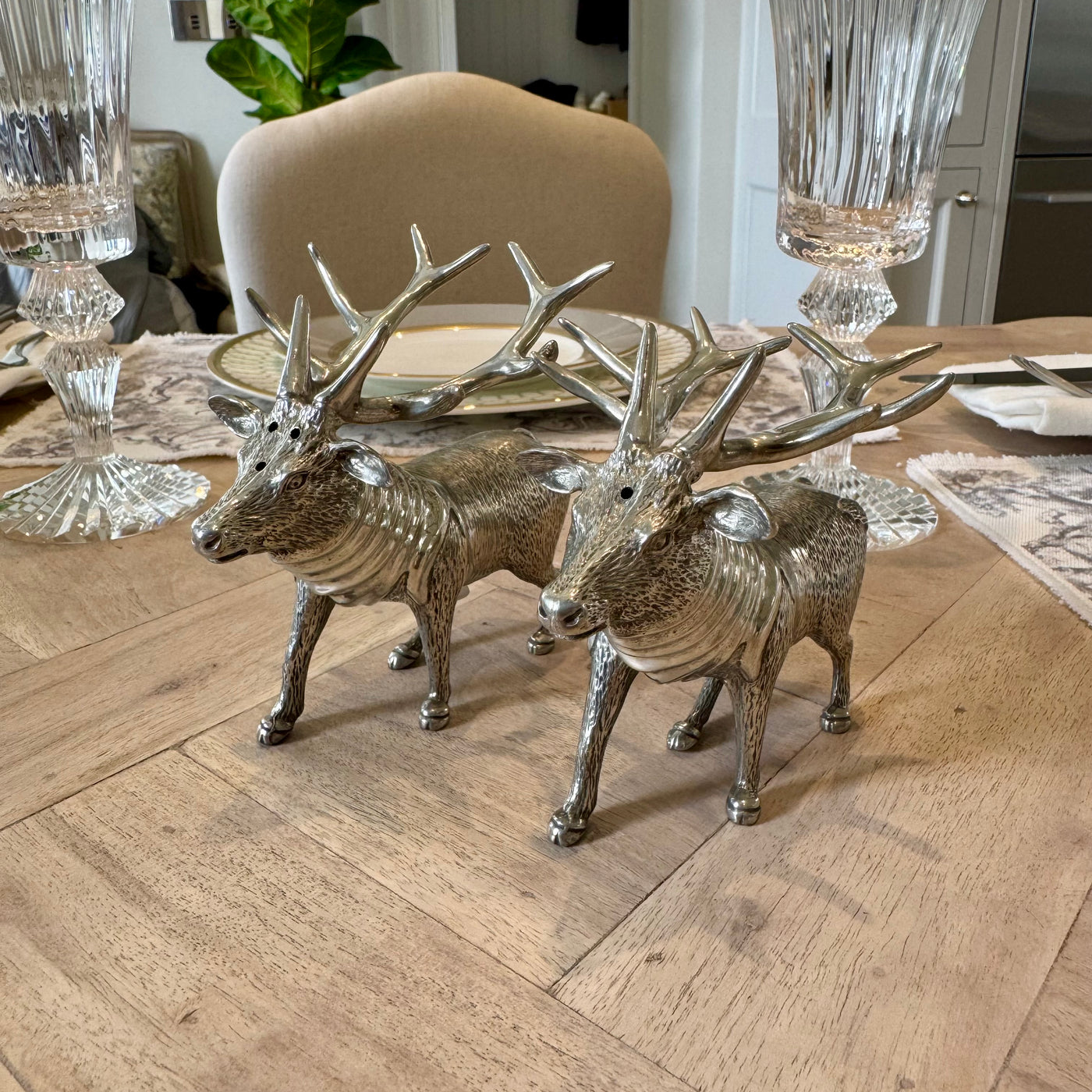 Textured pewter stag salt and pepper shakers with branching antlers on a wooden table