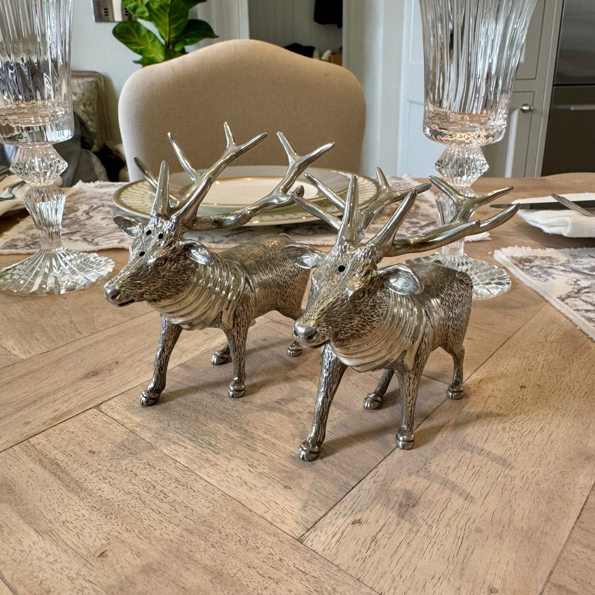 Textured pewter stag salt and pepper shakers with branching antlers on a wooden table