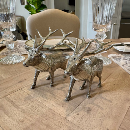 Textured pewter stag salt and pepper shakers with branching antlers on a wooden table