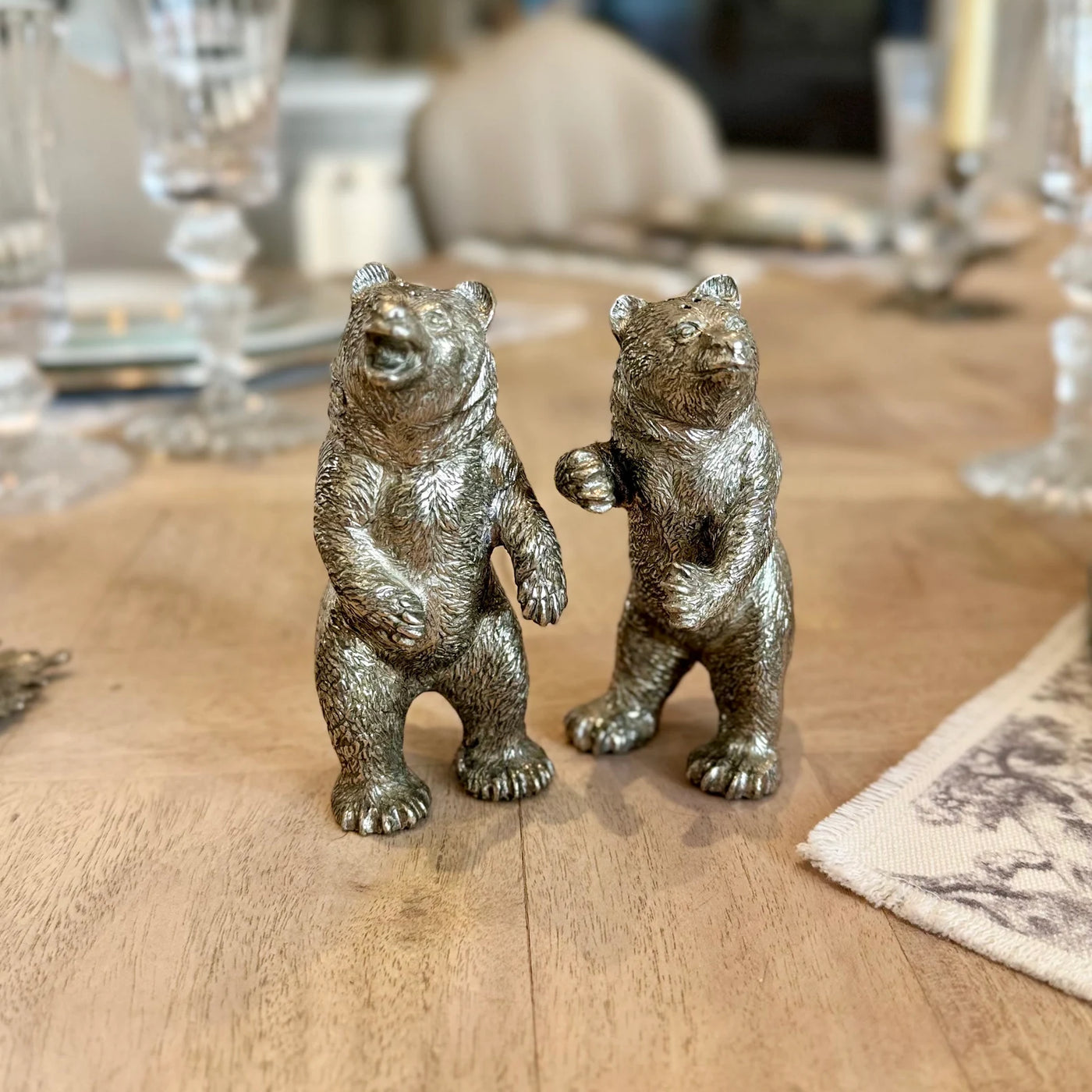Pair of standing pewter bear salt and pepper shakers in different poses on a dining table