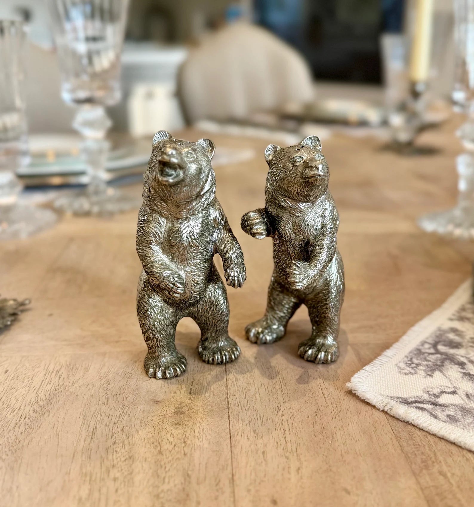 Pair of standing pewter bear salt and pepper shakers in different poses on a dining table