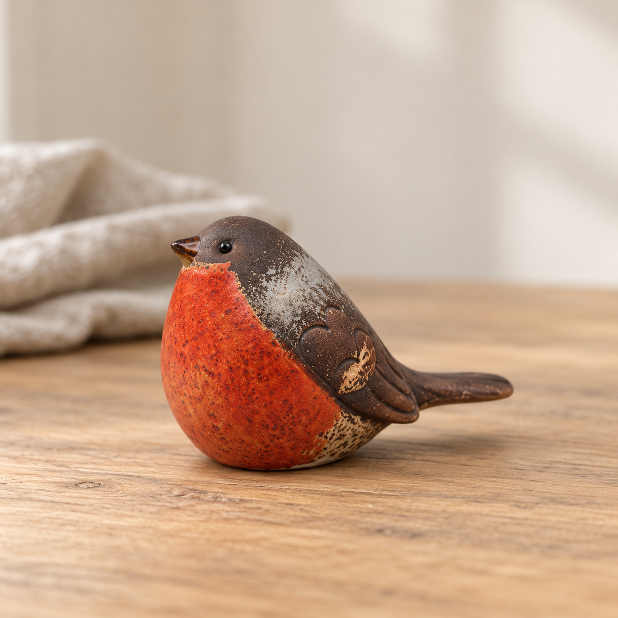 Traditional matte ceramic robin with brown wings and orange-red breast on pale oak