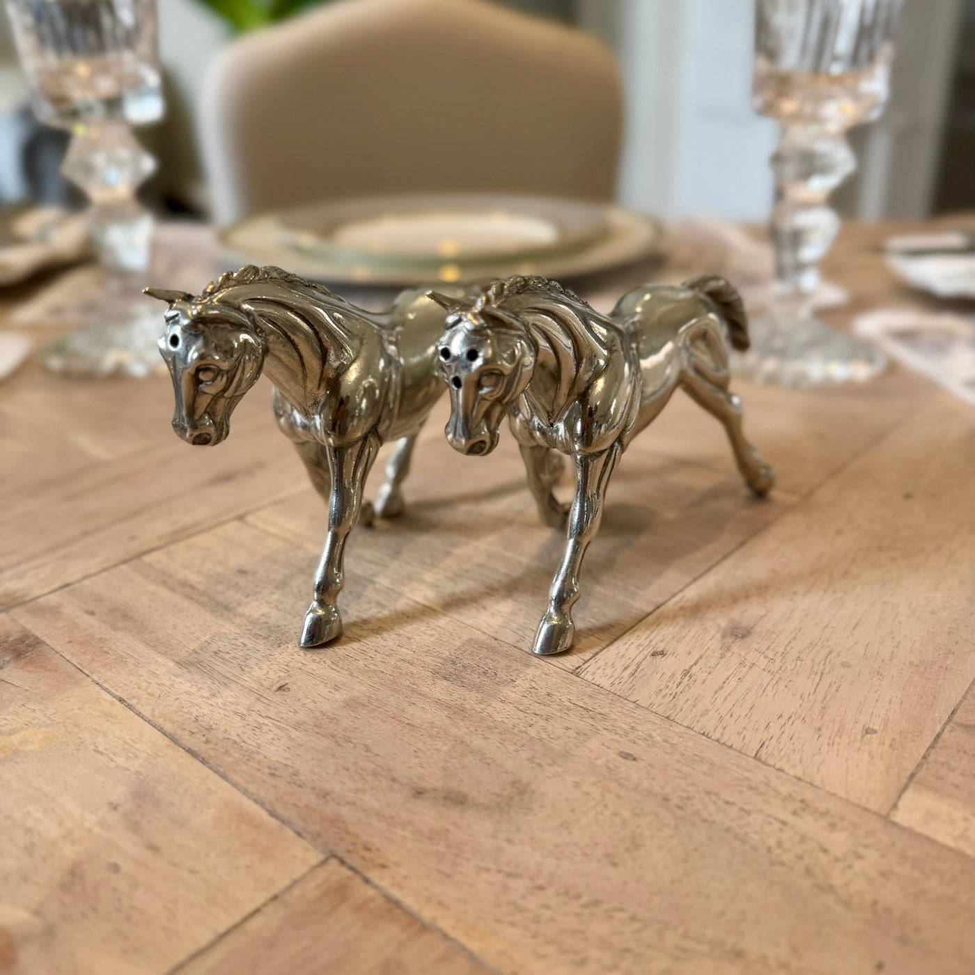 Side view of the pewter horse shaker pair on a wooden dining table