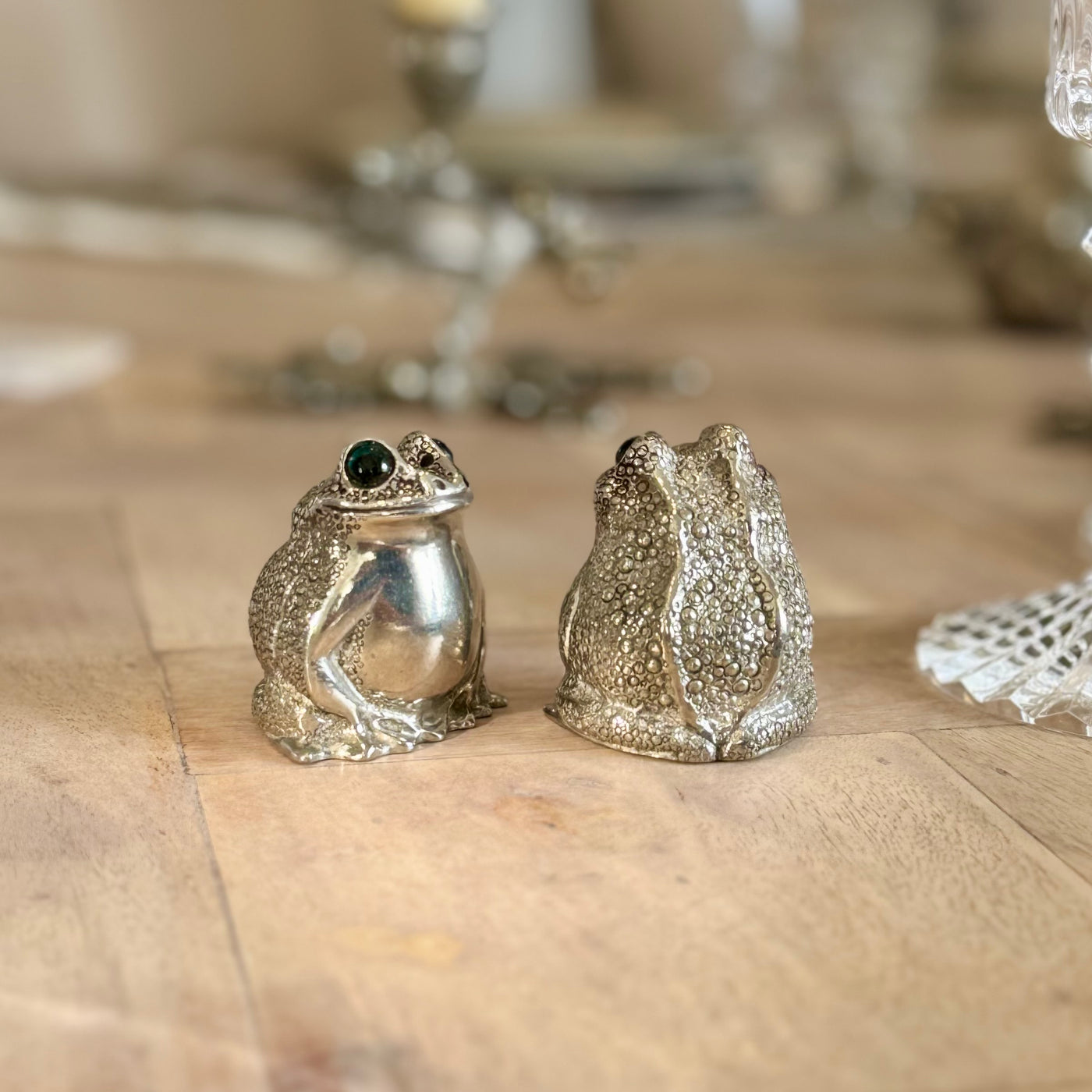 Pewter frog salt and pepper shakers showing a polished front and textured back on a wooden table