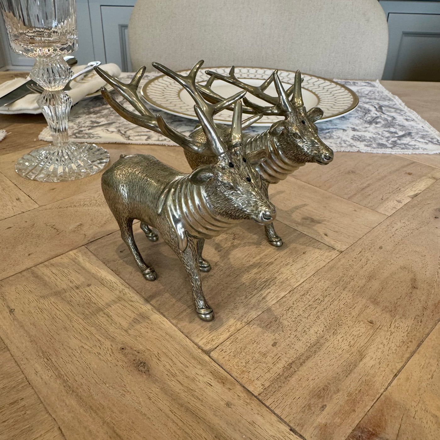 Angled view of the textured pewter stag shaker pair beside a place setting