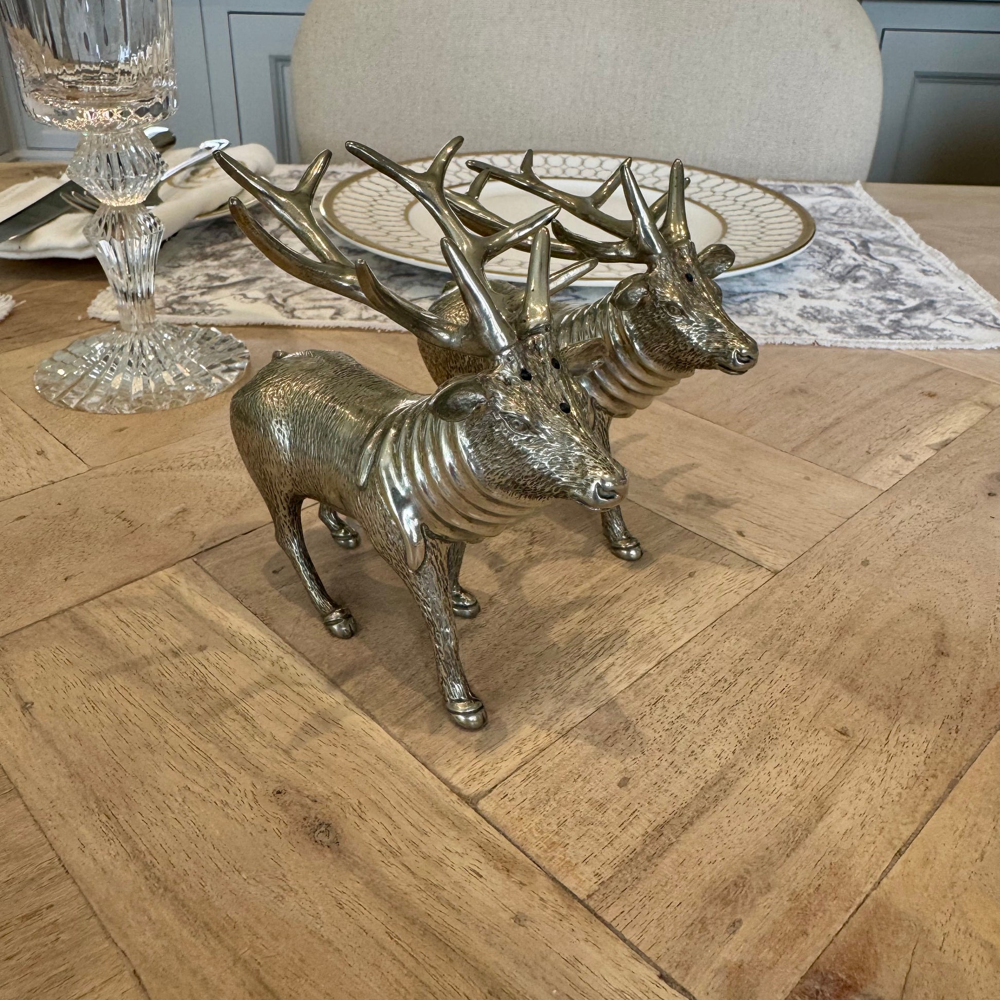 Angled view of the textured pewter stag shaker pair beside a place setting