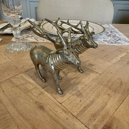 Angled view of the textured pewter stag shaker pair beside a place setting