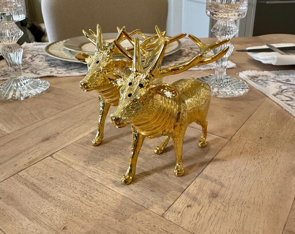 Gold plated stag salt and pepper set - side view showing intricate detail on a table with place settings