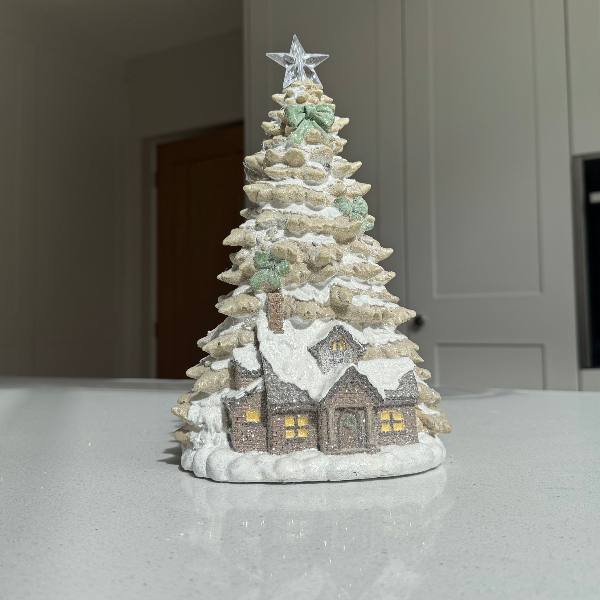 LED Christmas cottage beneath snowy tree with illuminated star