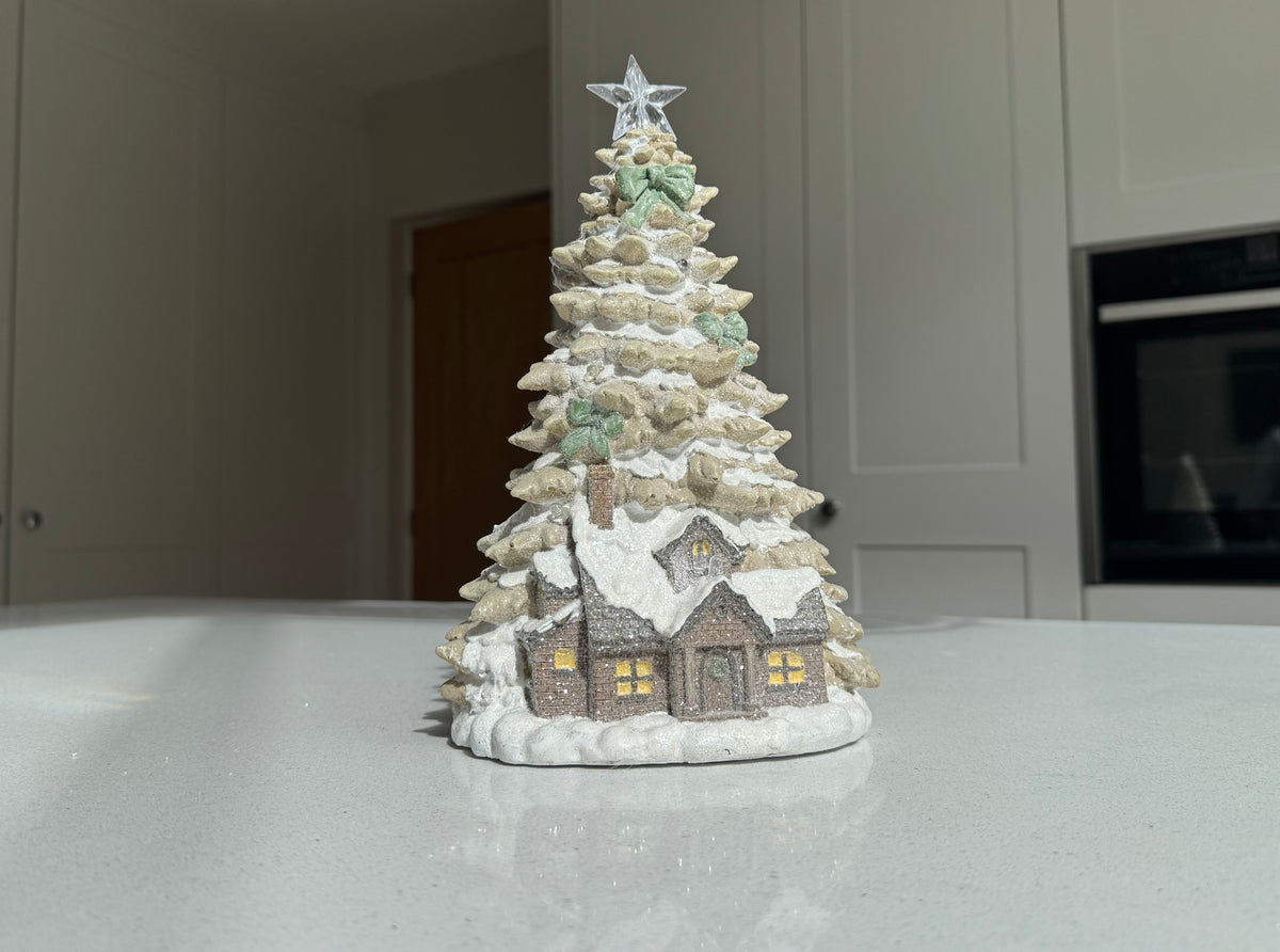 LED Christmas cottage beneath snowy tree with illuminated star