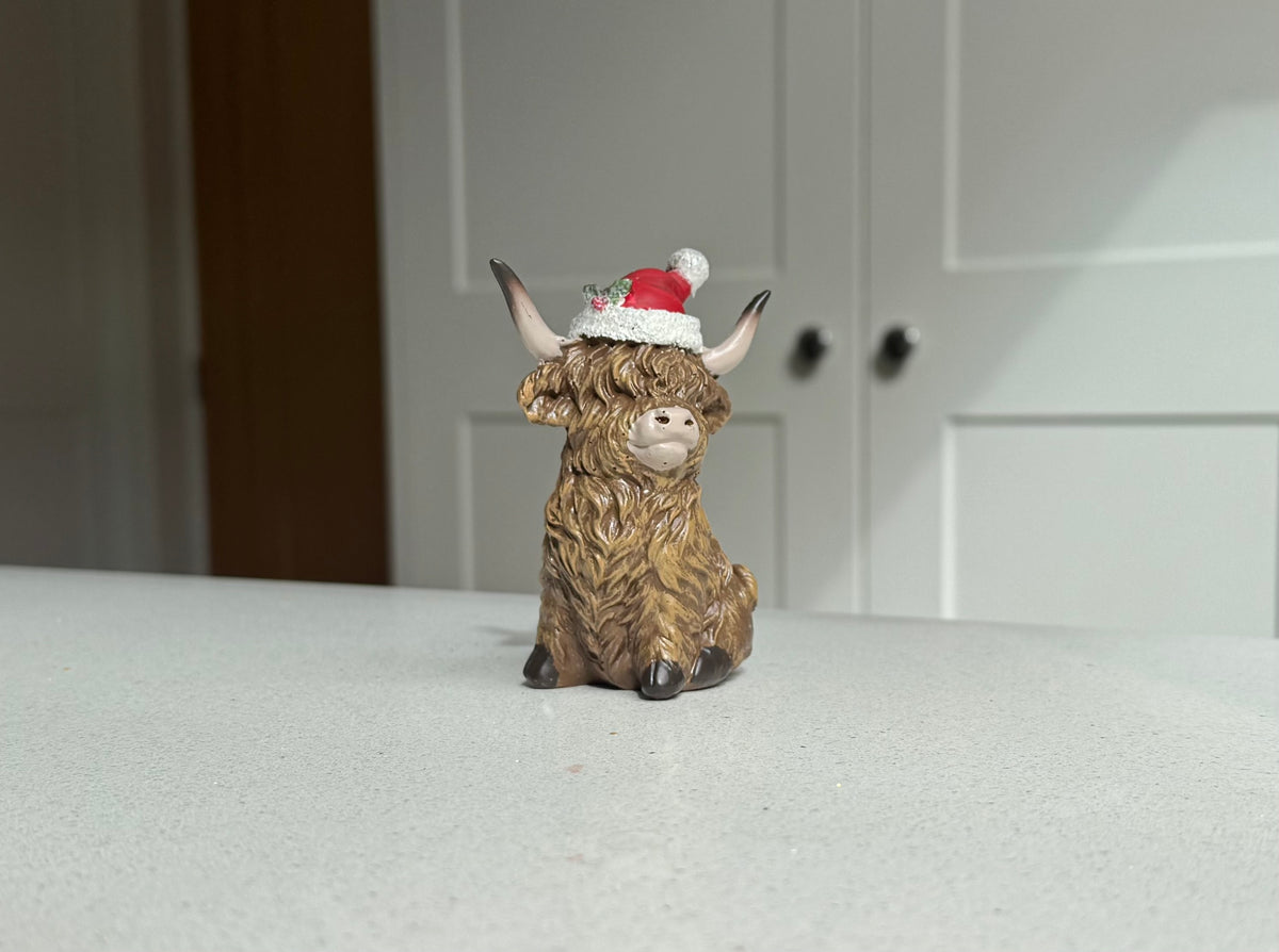 Sitting Highland Cow Ornament with Santa Hat – 9.5cm