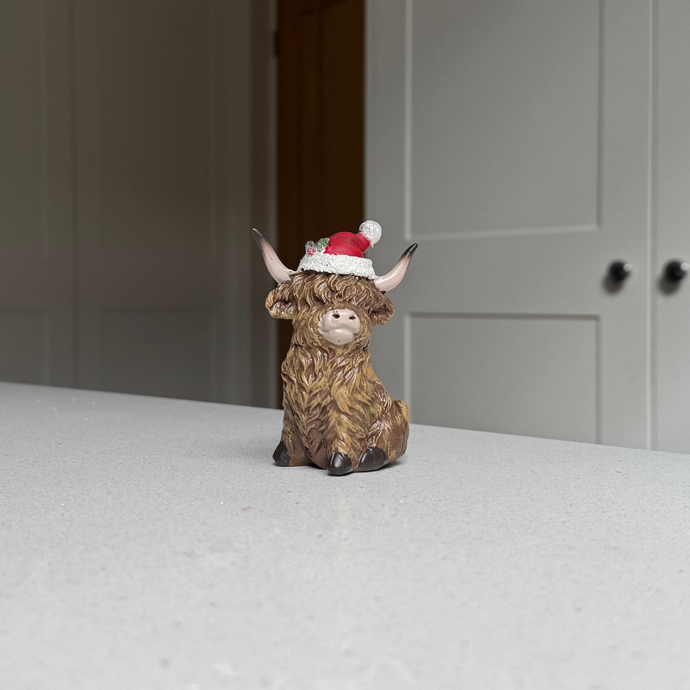 Sitting Highland Cow Ornament with Santa Hat – 9.5cm
