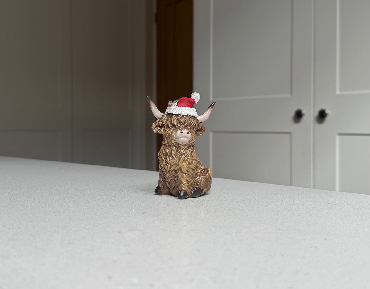 Sitting Highland Cow Ornament with Santa Hat – 9.5cm