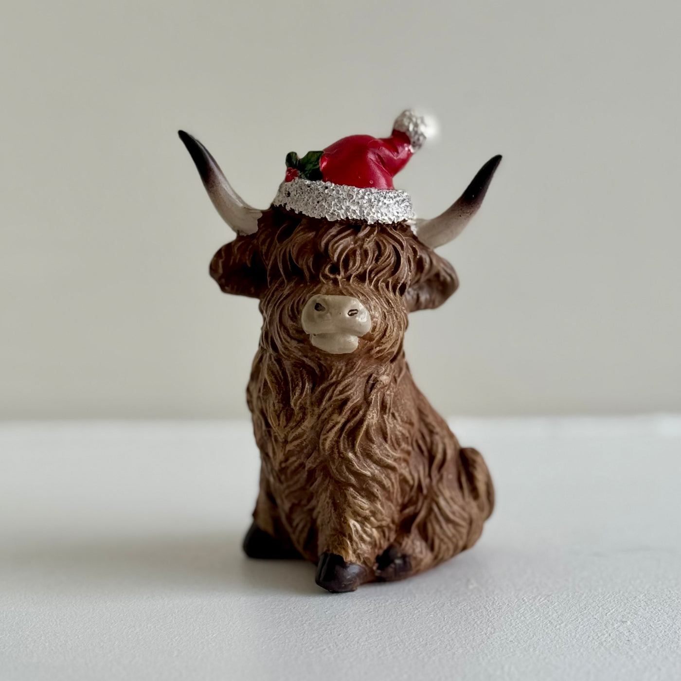 Sitting Highland Cow Ornament with Santa Hat – 9.5cm