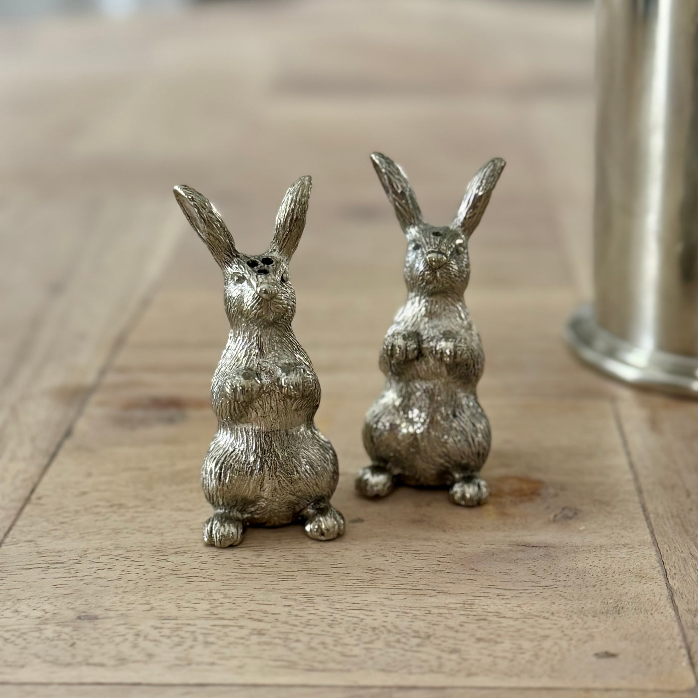 Mini pewter rabbit salt and pepper shakers standing beside a candle holder