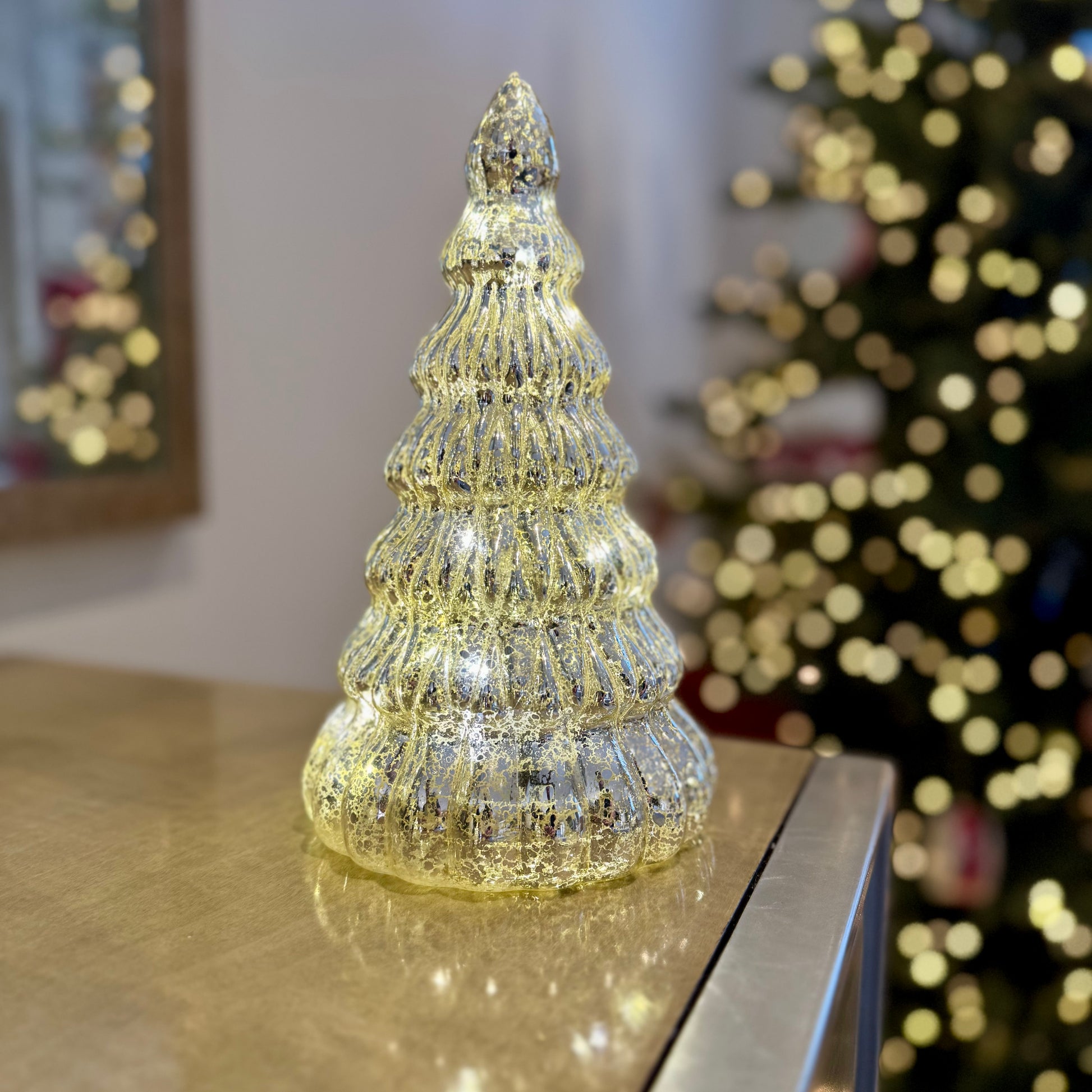 Light-up glass Christmas tree in festive display