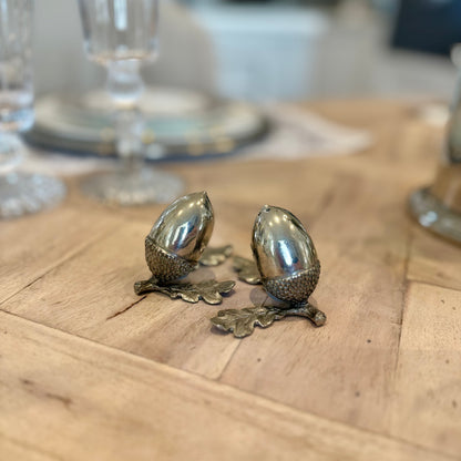 Pewter acorn salt and pepper shakers with oak leaf bases on a wooden dining table