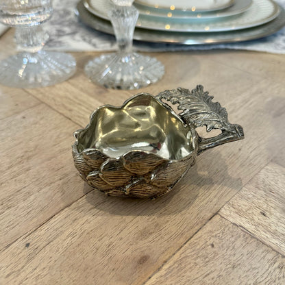 Open pewter artichoke salt pot with layered leaves and a sculpted leaf handle on a wooden table