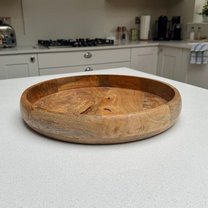 Round natural wood serving tray with raised rim