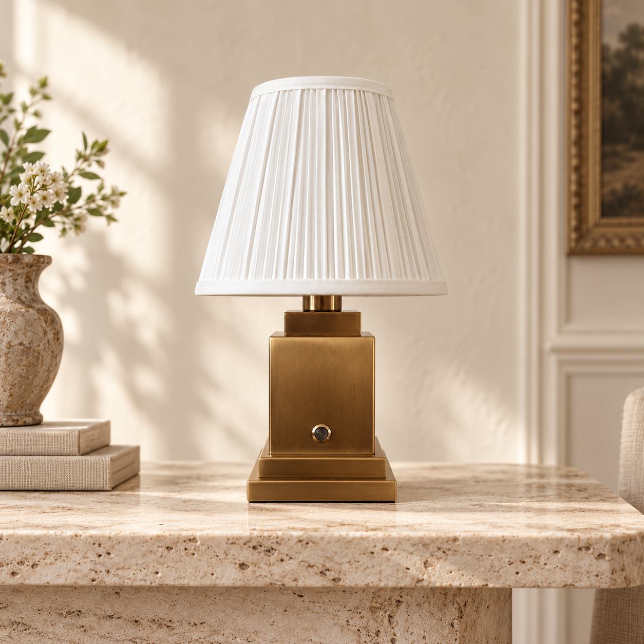 Beaumont brushed gold rechargeable lamp with white pleated shade on a travertine console