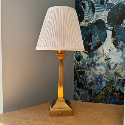Brushed gold rechargeable table lamp with slim square base and white pleated shade detail