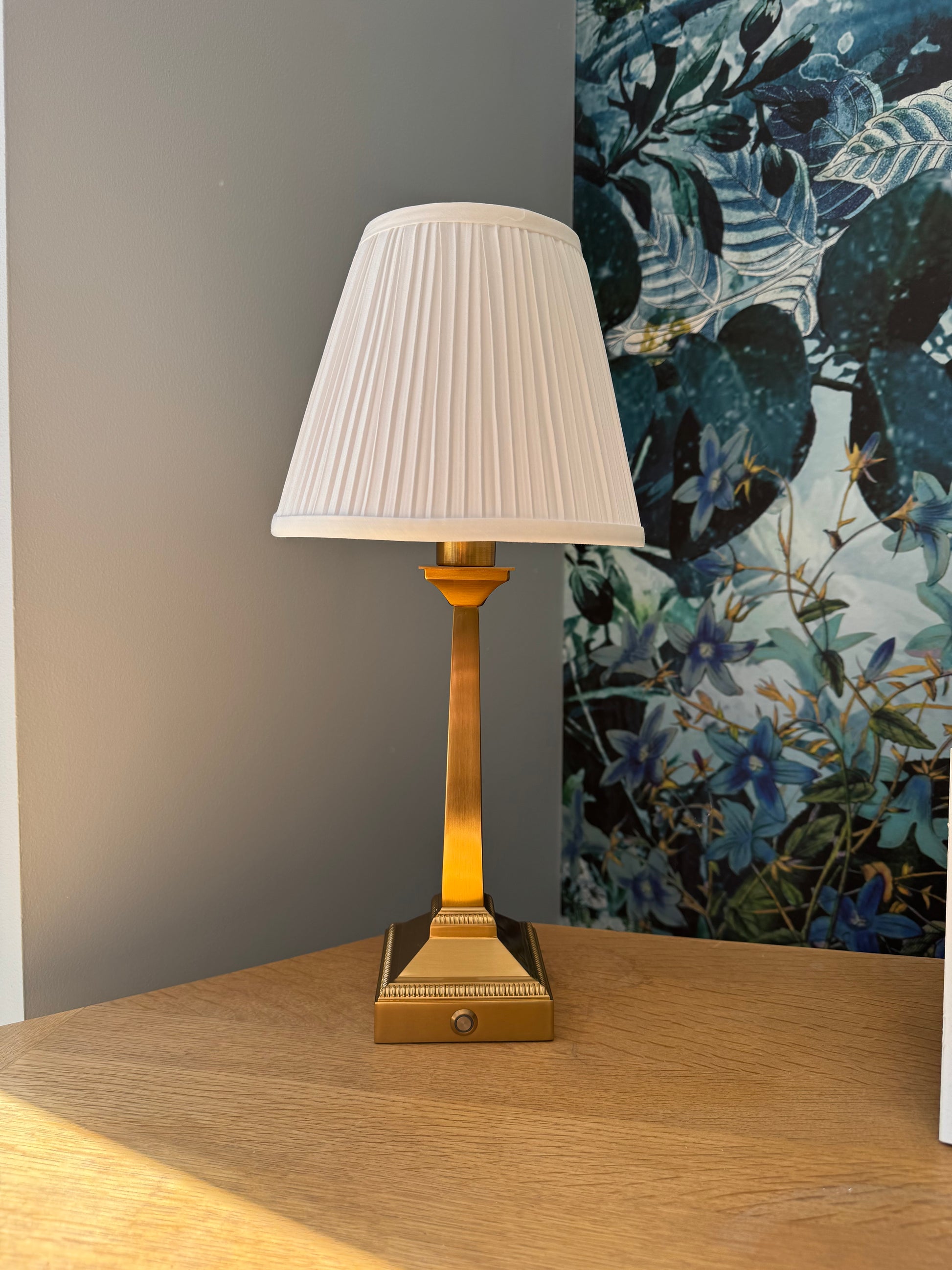 Brushed gold rechargeable table lamp with slim square base and white pleated shade detail