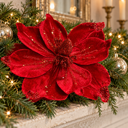 Handmade crimson red velvet poinsettia styled in a fir garland on a Christmas mantel.