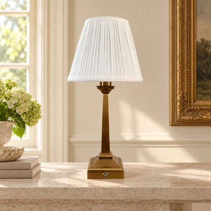 Mayfair brushed gold rechargeable table lamp with white pleated shade on travertine console